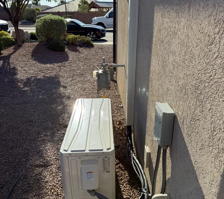Ductless mini-split condenser freshly installed on the exterior wall of a St. George home