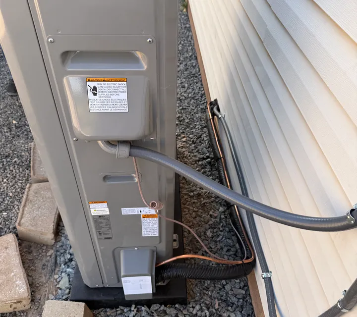 Close inspection of a condenser's electrical and refrigerant line connections during a repair visit